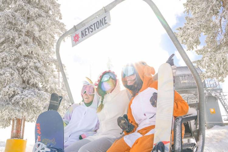 4 people sitting on a ski chair lift in the winter 