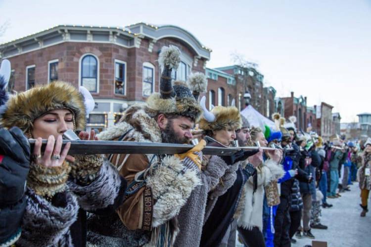 People Dressed in fuzzy hats and scarves doing the worlds longest shot ski